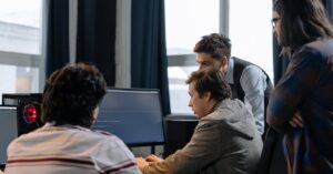 Quatro homens em ambiente de trabalho colaborando em um computador